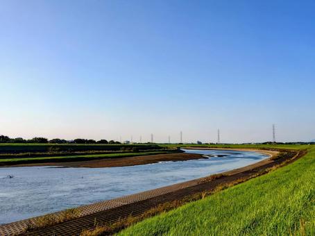 河川敷から眺める鉄塔と川の流れ 河川敷から眺める鉄塔と川の流れの写真