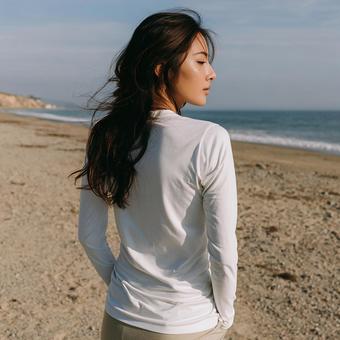 ビーチで海を眺める白い長袖Tシャツの女性 ビーチで海を眺める白い長袖Tシャツの女性の写真