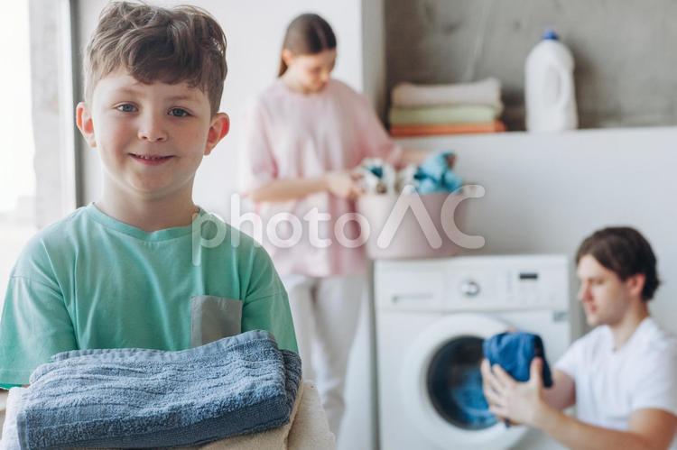 微笑んで洗濯物を持っている男の子と家族 家族,3人,男性の写真素材