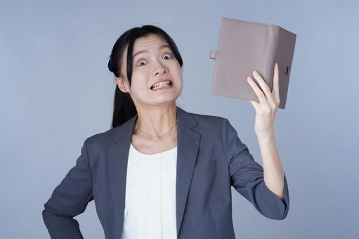 グレーの服の女性がファイルを掲げる 女性,手帳,本の写真素材