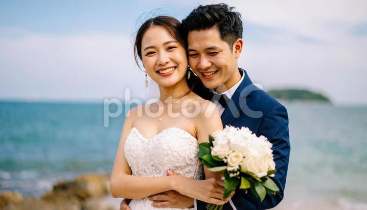 ブーケを持ち抱き合う新郎新婦 海,ウエディング,結婚の写真素材