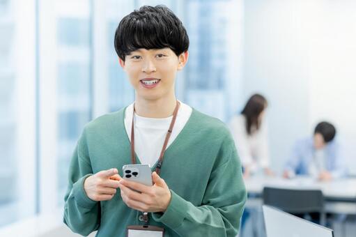 オフィスでスマホを使うビジネスマン スマホ,ビジネスマン,笑顔の写真素材