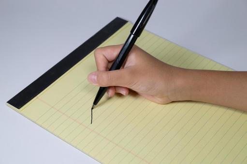 黄色いレポート用紙にペンで文字を書く手元 手,レポート用紙,書くの写真素材
