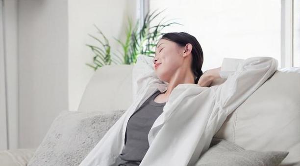ソファで伸びをするアジア人女性 ソファで伸びをするアジア人女性 女性,伸び,ストレッチの写真素材