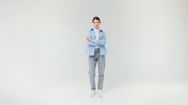 カメラ目線で腕組みをするジーンズ女性 カメラ目線で腕組みをするジーンズ女性の写真