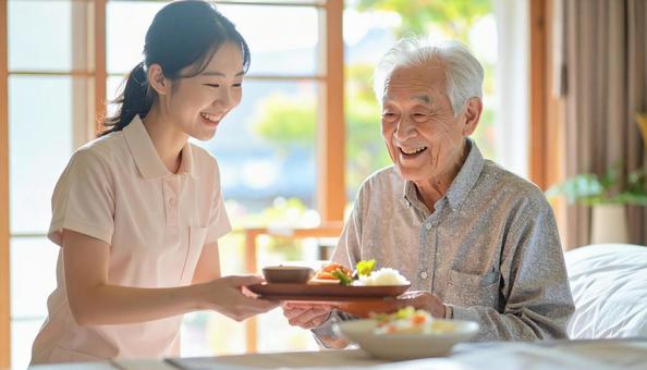 高齢男性と女性介護士の穏やかな食事風景 高齢男性と女性介護士の穏やかな食事風景の写真