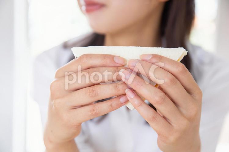爽やかにサンドウィッチを頬張る女性 料理,白,グレーの写真素材