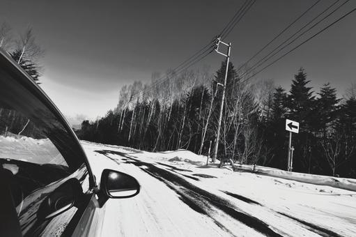 雪道を走るモノクロの冬のドライブ風景 雪道を走るモノクロの冬のドライブ風景の写真