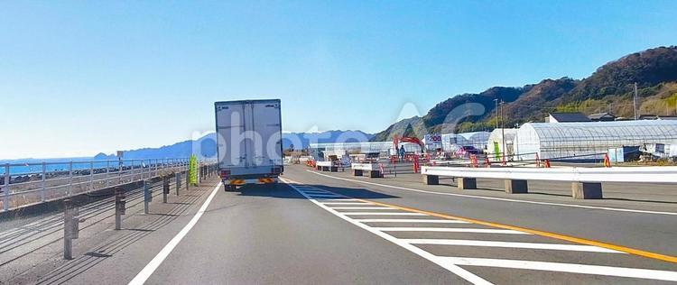 苺のビニールハウスが並び立つ海岸道路風景 シーサイドロード,トラック,ビニールハウスの写真素材
