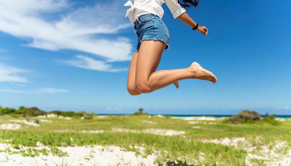 砂浜をジャンプする女性の足の写真