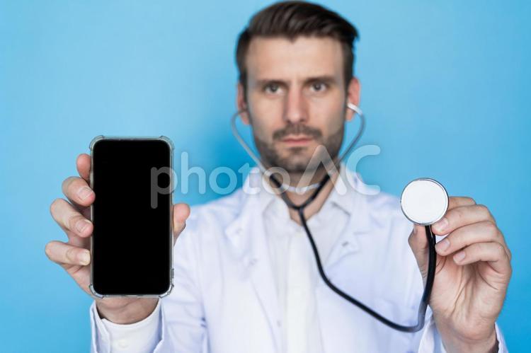 カメラ目線でスマートフォンと聴診器を持つ男性 男性,ヒゲ,携帯の写真素材