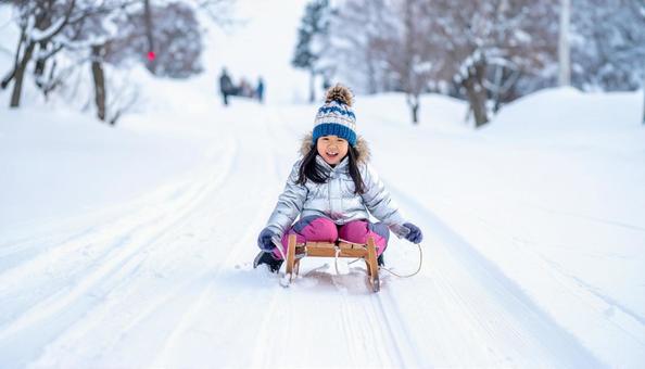 雪の中、そりで遊ぶ日本人の女の子 雪の中、そりで遊ぶ日本人の女の子の写真