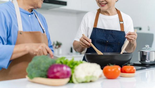 家のキッチンで料理を作るシニア世代夫婦 家のキッチンで料理を作るシニア世代夫婦の写真