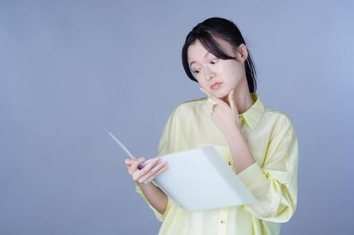 資料を見て考える黄色い服の女性 女性,バインダー,ファイルの写真素材