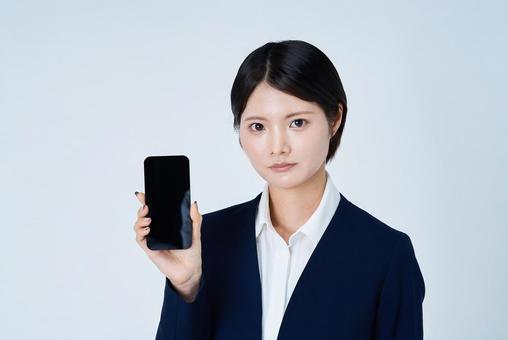 スマートフォンを操作するスーツ姿の女性 スマートフォンを操作するスーツ姿の女性 女性,ビジネスウーマン,キャリアウーマンの写真素材
