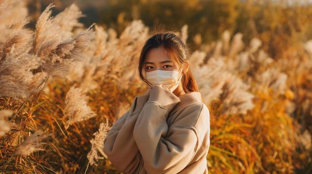 秋風に揺れるススキとマスク姿の女性 秋風に揺れるススキとマスク姿の女性の写真