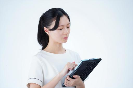 女性がタブレットを持って操作する 女性,タブレット,持つの写真素材