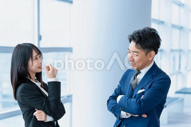 廊下で談笑するビジネス系男女二人組 ビジネスマン,ビジネスウーマン,男性の写真素材
