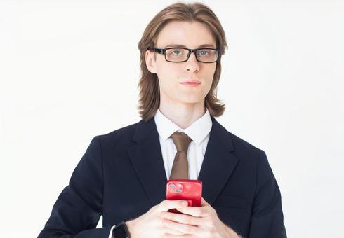 スマートフォンを使うスーツにメガネのカメラ目線の男性 男性,外国人,欧米人の写真素材