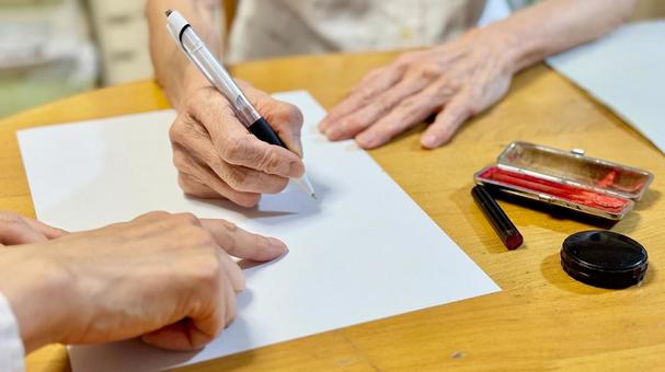 高齢女性に記入箇所を指示する女性と印鑑 高齢女性に記入箇所を指示する女性と印鑑 遺言,書類,捺印の写真素材