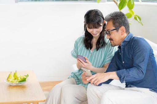 リビングでスマホを見るミドルの夫婦 夫婦,家族,ミドルの写真素材