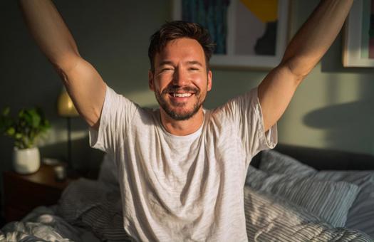 朝日を浴びて伸びをする男性の写真