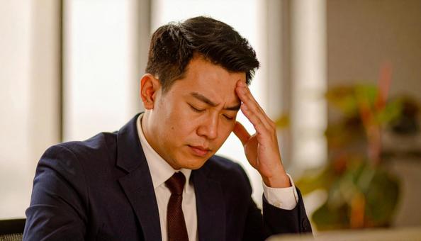 頭を押さえて悩む男性ビジネスマンの写真