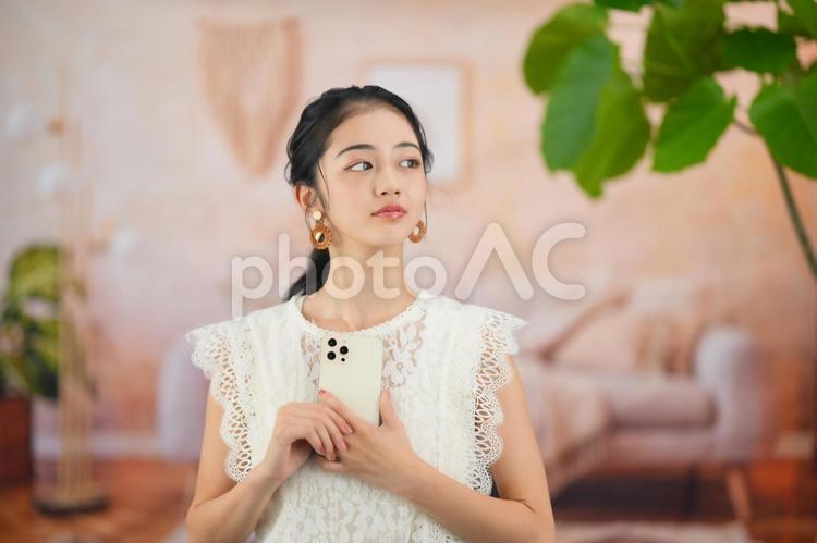 スマホを持ち横を見る女性 女性,スマホ,持つの写真素材