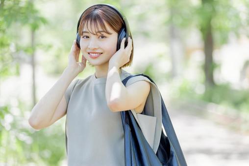 新緑の中ヘッドフォンで音楽を聴く若い女性 新緑の中ヘッドフォンで音楽を聴く若い女性 女性,外出,ヘッドフォンの写真素材