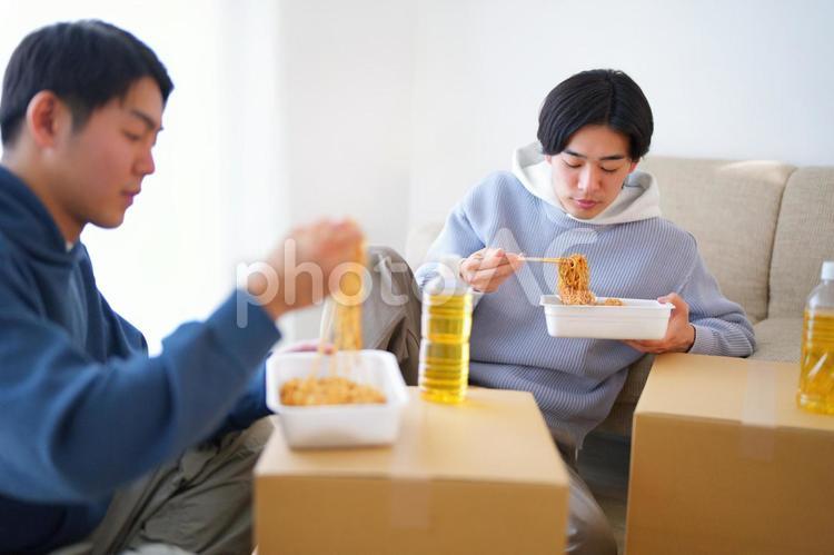 引っ越しの合間にカップ焼きそばを食べる2人の男性 引っ越し,一人暮らし,男性の写真素材