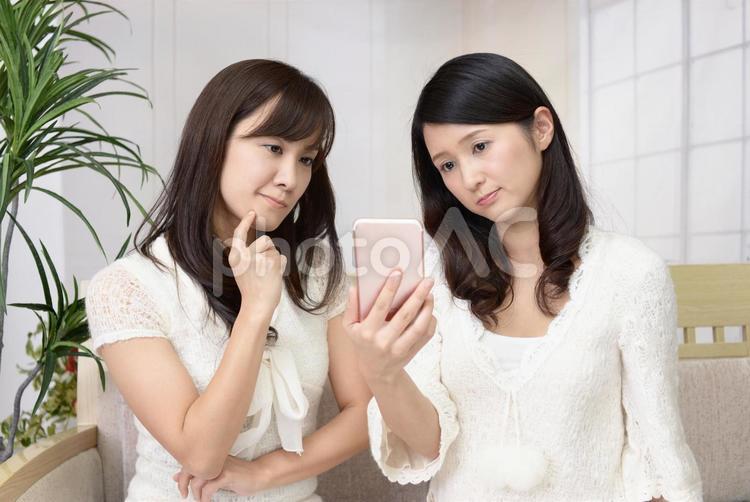 困惑した表情の二人の女性 女性,女,スマートフォンの写真素材