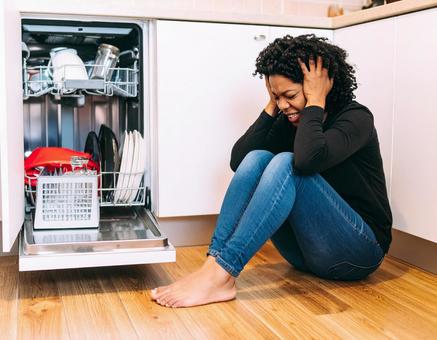 食洗機トラブルに頭を抱える女性 食洗機トラブルに頭を抱える女性の写真