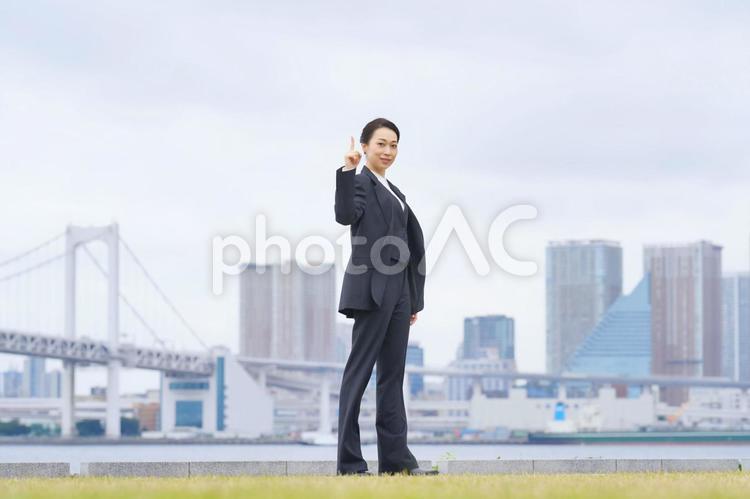 指を一本立ててカメラ目線で微笑む女性（全身） 女性,キャリアウーマン,カメラ目線の写真素材