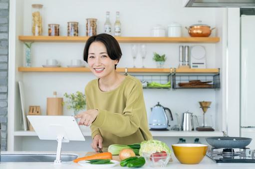 キッチンで調理するミドルの女性 キッチンで調理するミドルの女性の写真