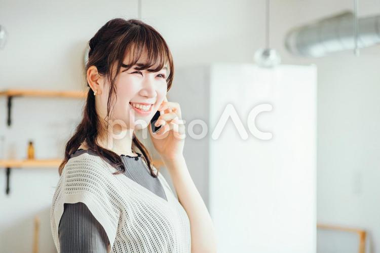 家でスマホを使う女性（通話・笑顔） 電話,スマホ,通話の写真素材