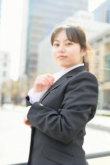 ビル街でカメラ目線のスーツの女性 ビル街でカメラ目線のスーツの女性 日本人,女性,20代の写真素材