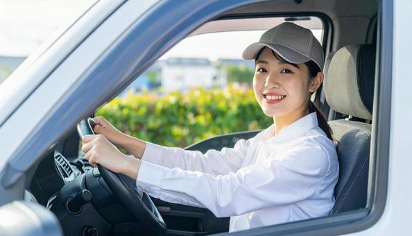 ハンドルを握る可愛い配送スタッフの女性の写真