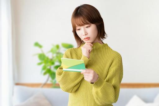 通帳を見て考える女性 女性,家計,やりくりの写真素材