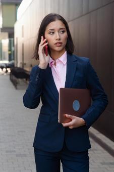街なかで電話しているパンツスーツの女性 ビジネスウーマン,ビジネス,女性の写真素材