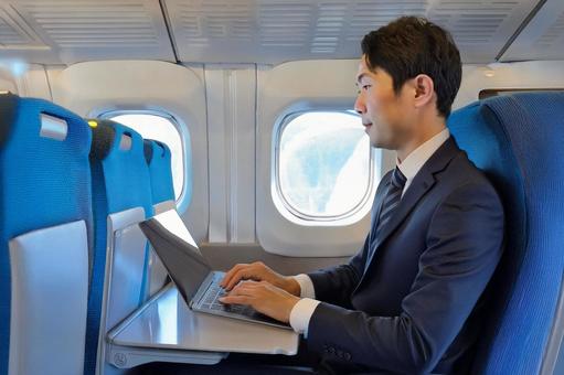 新幹線でPCワークをする男性の写真