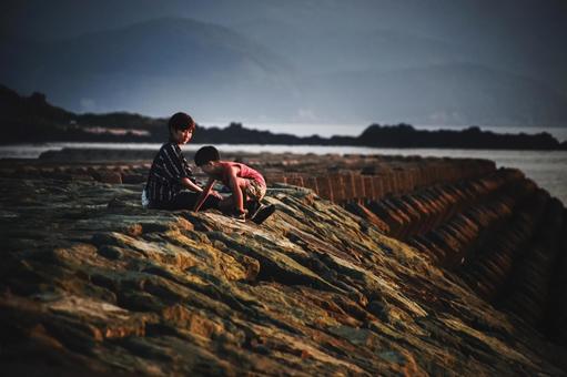 ＜素材＞夕方の防波堤で海を眺める親子 家族,親子,女性の写真素材