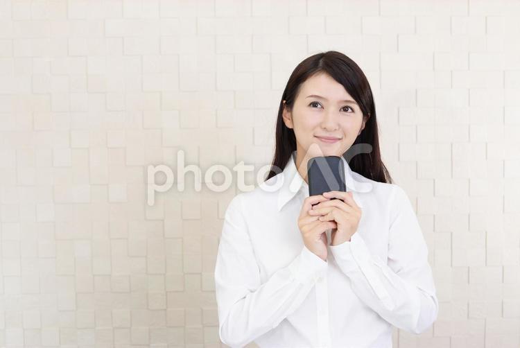 スマートフォンを持ち微笑む女性 女性,スマートフォン,女の写真素材