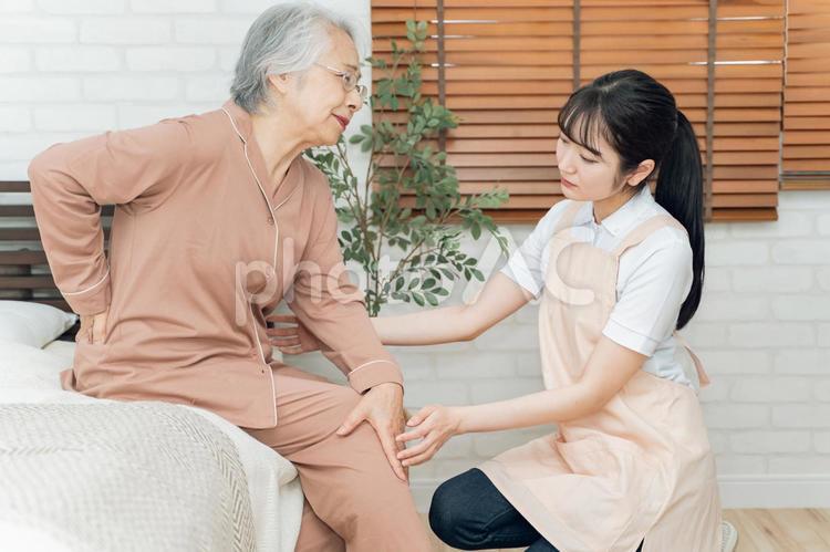 痛がる高齢者女性とエプロン姿の女性（腰痛） 高齢者,腰痛,ヘルニアの写真素材