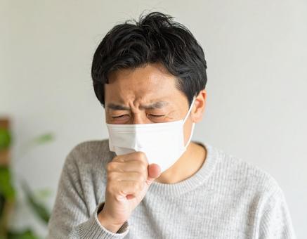 マスクを着用して咳をするの男性 マスクを着用して咳をするの男性の写真