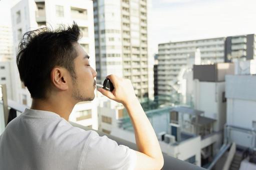 ベランダで電子煙草を吸う男性 ベランダで電子煙草を吸う男性 ビジネスマン,男性,人物の写真素材