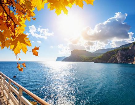 空と太陽、そして海と紅葉している山々 空と太陽、そして海と紅葉している山々の写真