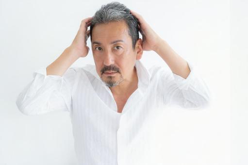 リビングでヘアケアをするミドルの男性 リビングでヘアケアをするミドルの男性 ヘアケア,育毛,ビューティーの写真素材