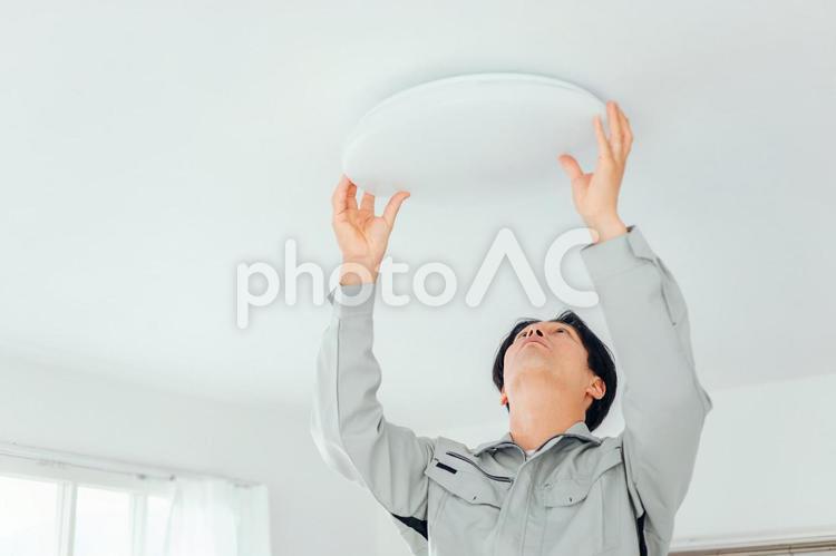 照明器具をチェックする作業着の男性 照明器具,照明,電気工事の写真素材