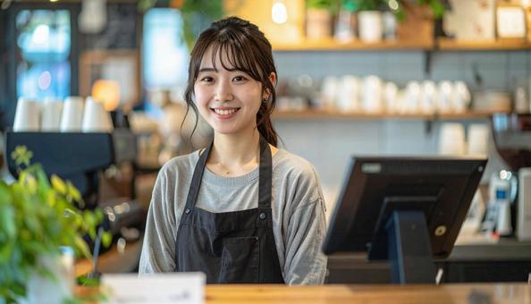 カフェで女性バリスタが笑顔で接客する様子の写真
