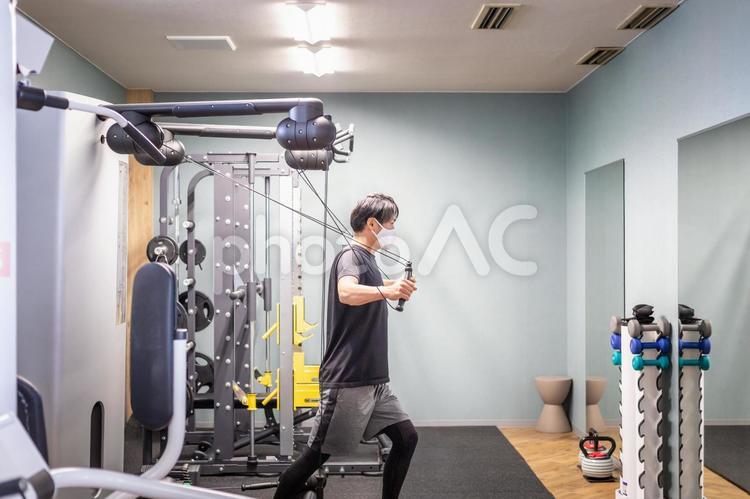 スポーツジムでケーブルマシンを使う男性（マスク） ケーブルマシン,ケーブル,ワークアウトの写真素材
